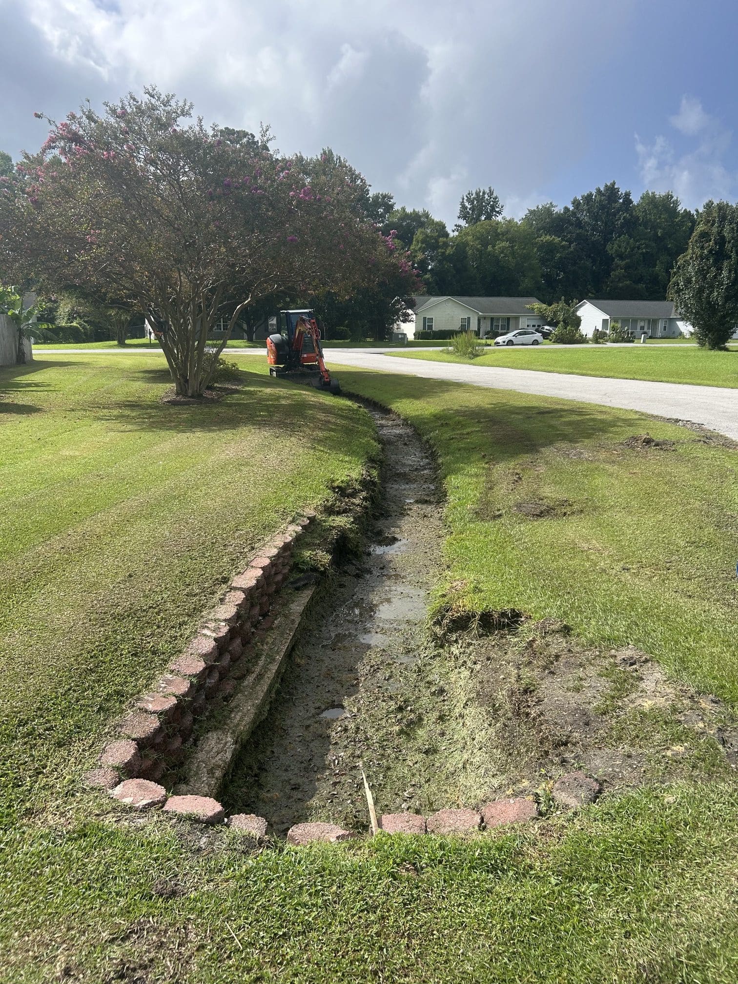 Compact track loader cutting the ditch profile back in along the road